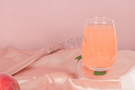 饮料海报摄影照片_一杯新鲜桃汁粉色背景