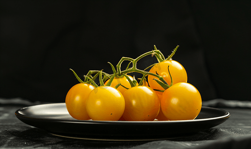 黑色背景中的黑色盘子上放着漂亮的黄色西红柿