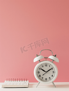 日历倒计时摄影照片_粉红色桌面背景上的白色闹钟和日历