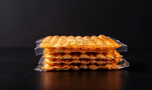 中纹理摄影照片_黑色背景中包装中的甜点心饼干面团制成的蜂蜜零食