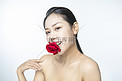医美美容护肤白天美女室内嘴巴上放玫瑰花摄影图配图