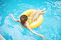夏天游泳白天坐在游泳圈里的美女泳池滑水摄影图配图