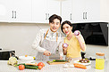 婚恋家庭白天一对年轻夫妇厨房里切菜做饭摄影图配图
