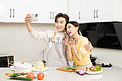 情侣白天一对情侣厨房里拿着手机自拍摄影图配图