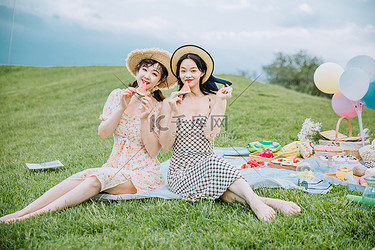 野餐郊游白天坐在草地上的闺蜜草地靠在一起摄影图配图