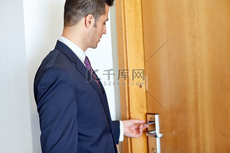 商务、安全和人的概念-在酒店房间或办公室门口有钥匙卡的商人。在酒店或办公室门口持有钥匙卡的商人