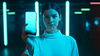 在霓虹灯下展示带空白屏幕手机的女性将手机拉伸到相机可用空间