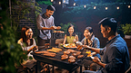 一群亚洲朋友在家庭花园的晚餐时间露营和烧烤
