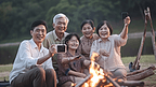 亚洲老人用智能手机给他的家人拍照，他们在湖边旅行和野餐，他们露营，用炉子烧烤，幸福的家庭活动