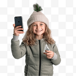 手拿手机自拍图片_有圣诞树的小女孩用智能手机给自