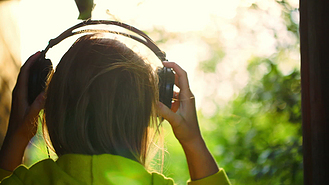 在户外戴着耳机听音乐的女孩