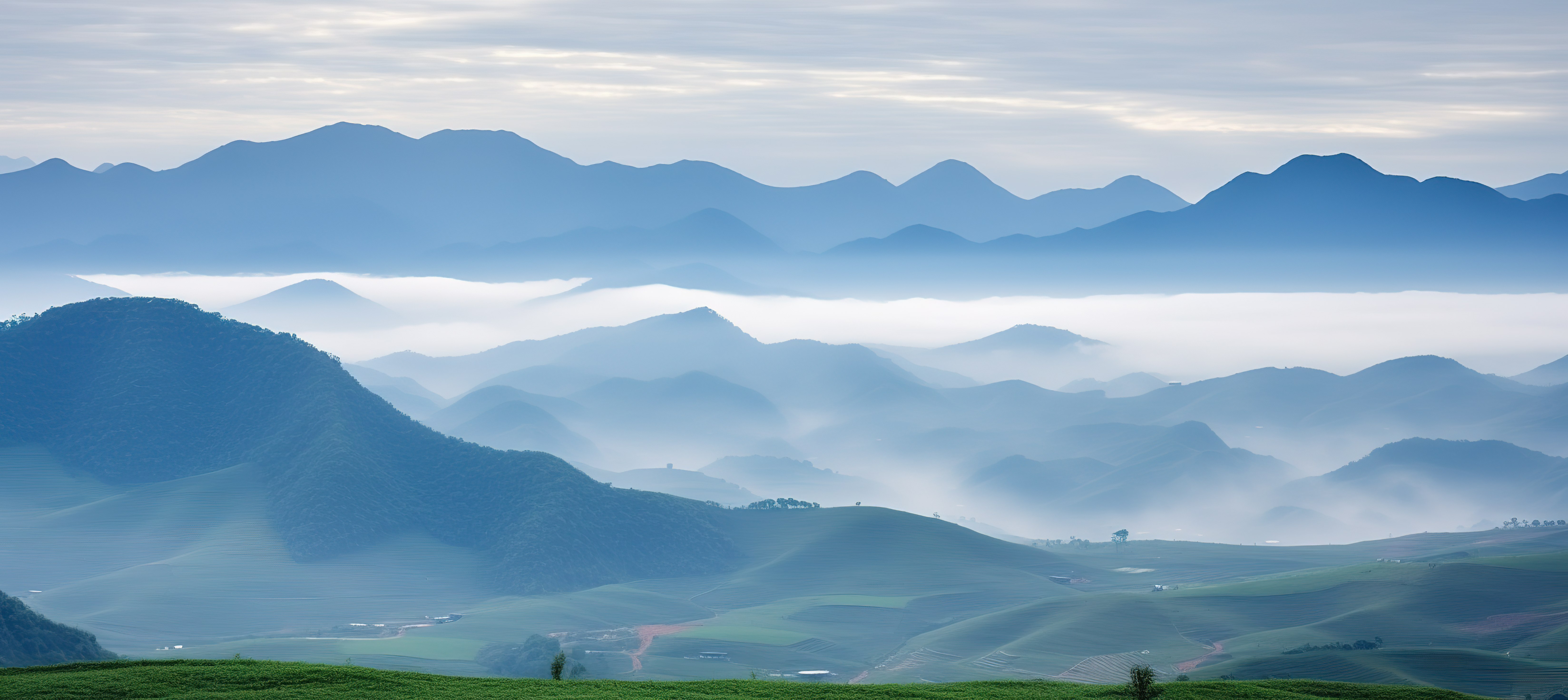 郁郁葱葱的绿色牧场，山景雾气和云彩图片