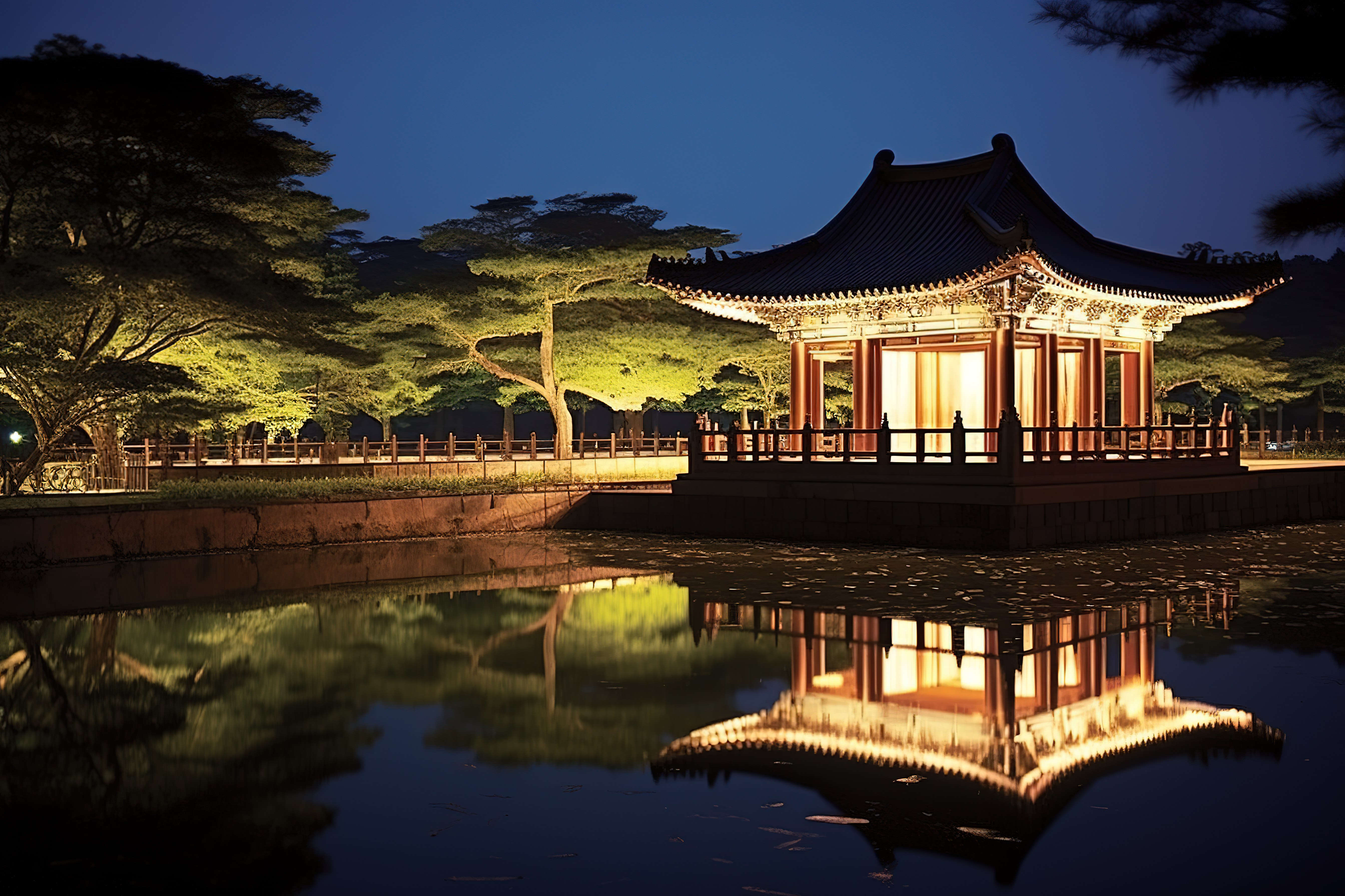 池塘边的一座中国凉亭在夜间亮起灯光图片