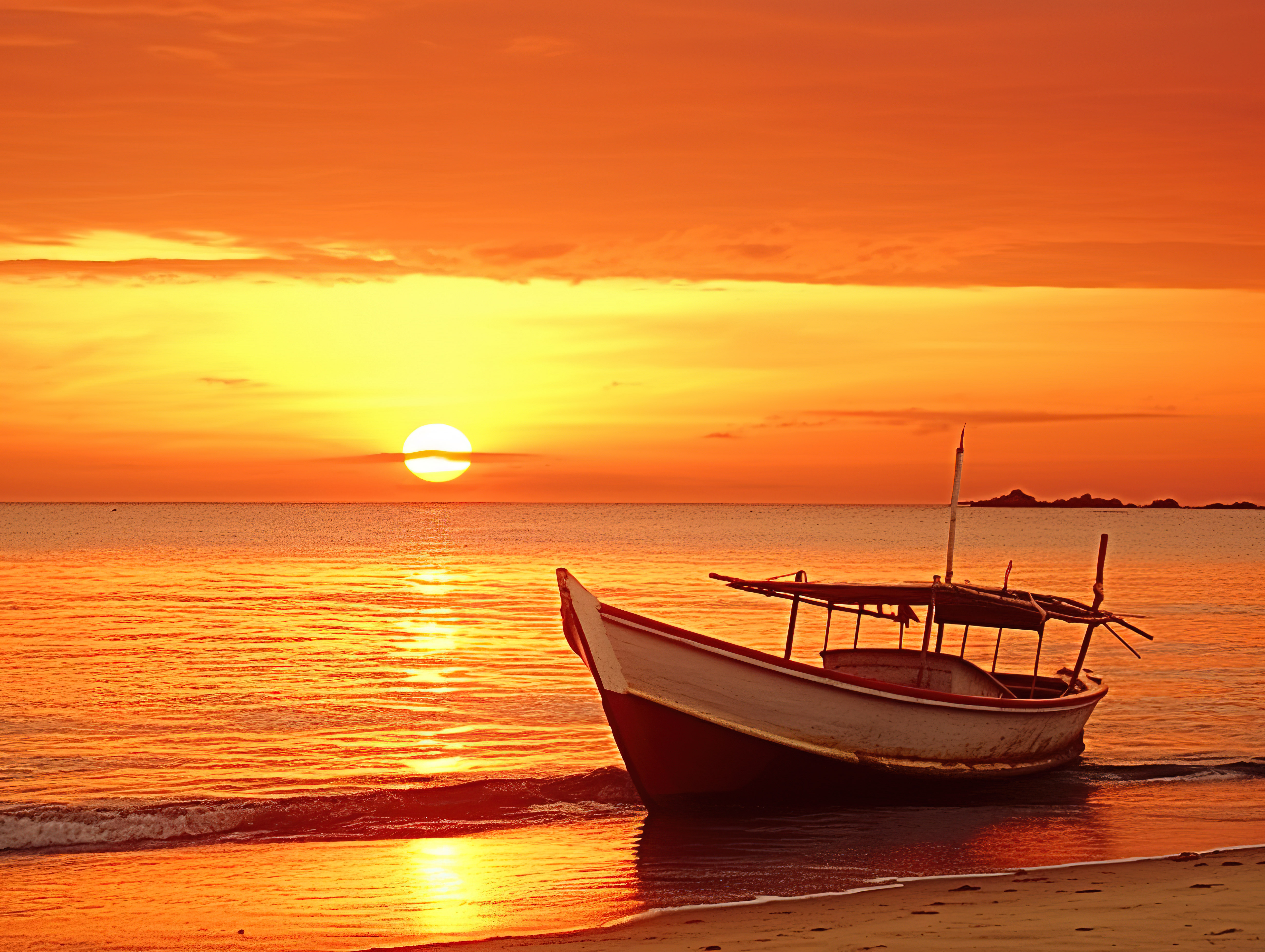 海滩上一艘旧的白色小船，日落时上面有橙色的天空图片