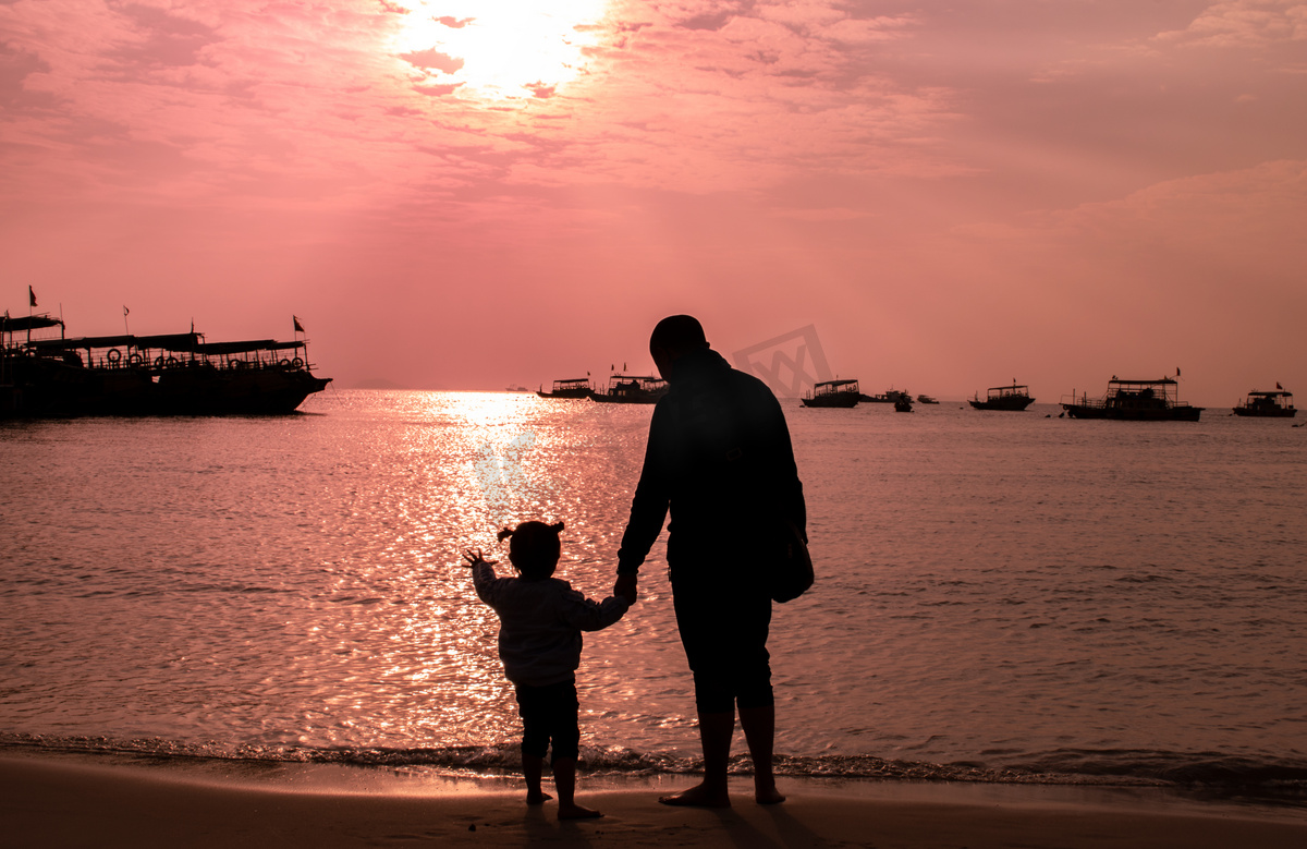 海边日落父亲拉着女儿的手看日落图片