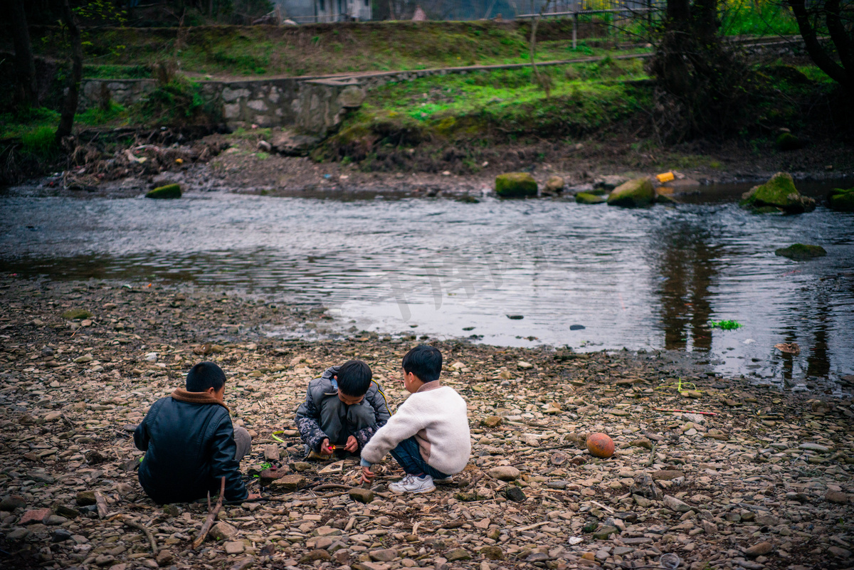小孩在河边玩耍春天三个小男孩农村小河滩上玩玩石头摄影图配图图片