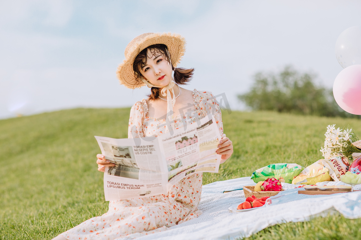 文艺夏天白天野餐的美女户外草地看报纸摄影图配图图片