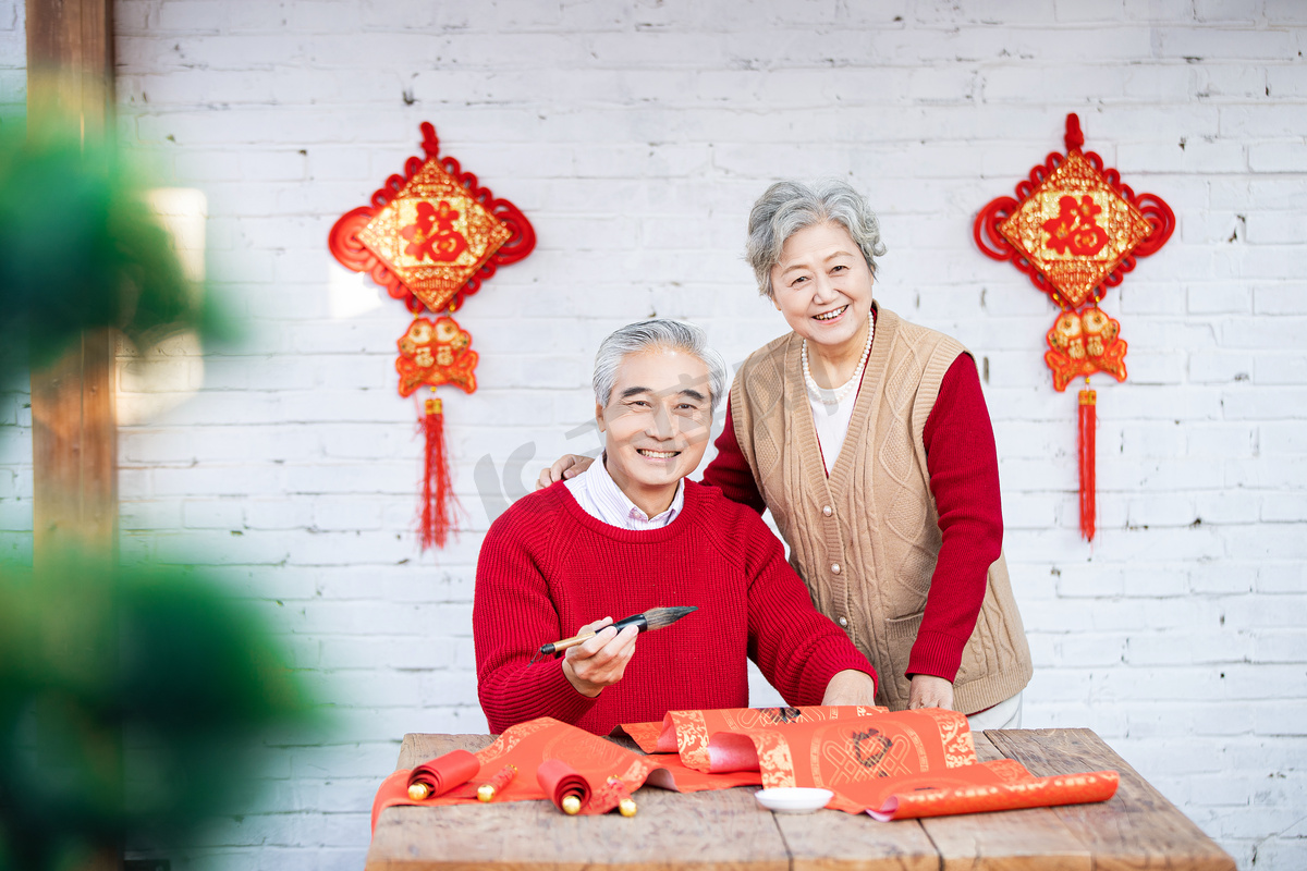 除夕手拿毛笔写字的爷爷和慈祥的奶奶摄影图配图图片