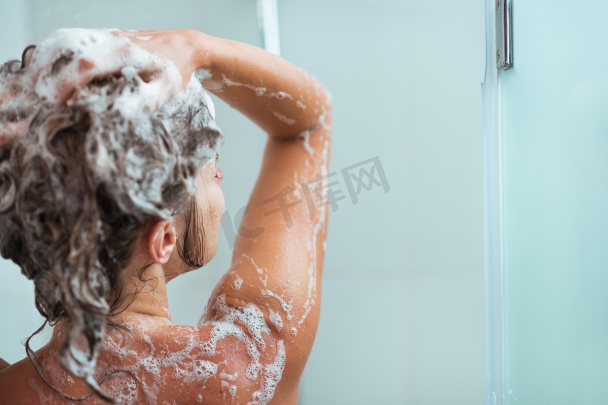 在淋浴洗发水的女人后视图图片