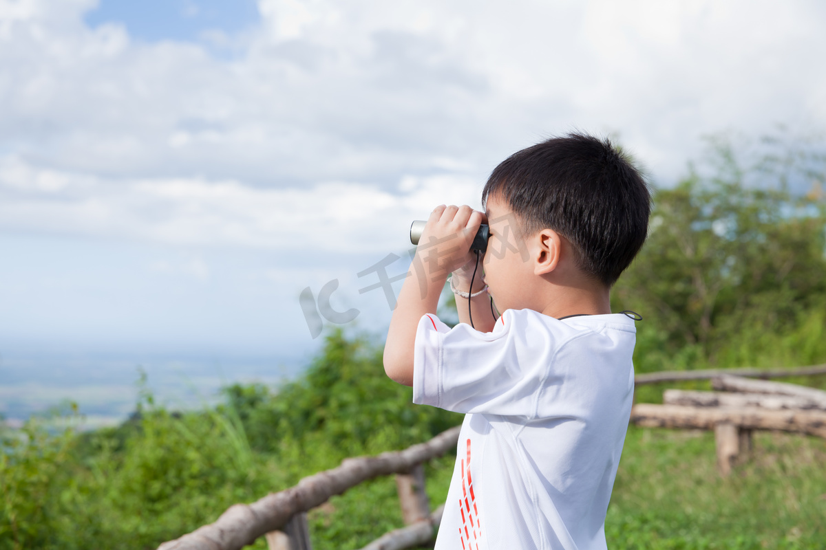 小的孩子看在双筒望远镜户外在阳光灿烂的夏天的一天 图片