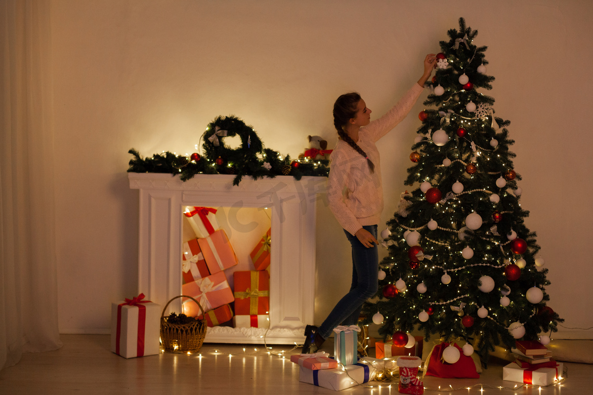 美丽的女人装饰圣诞树加兰灯新年假期图片