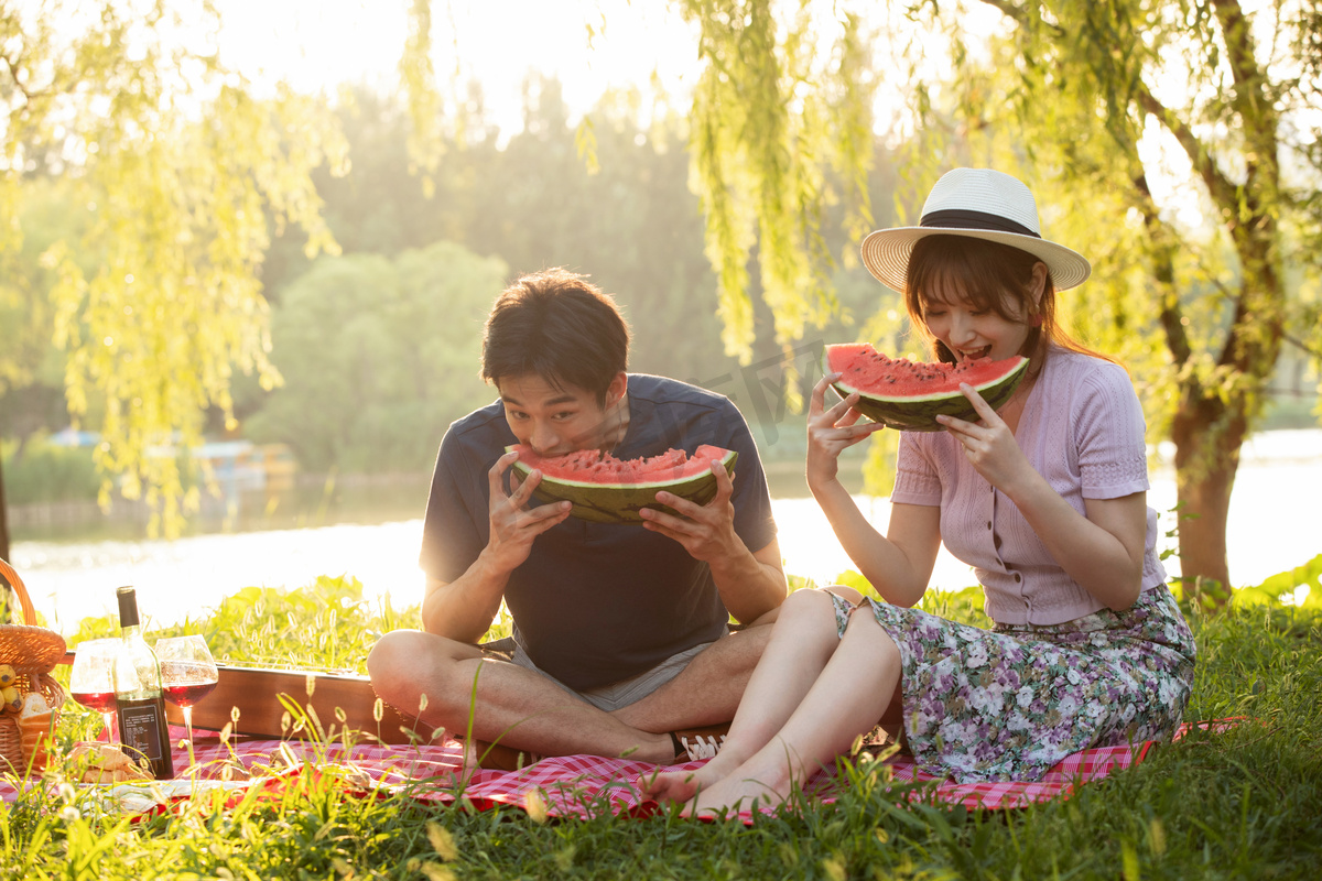 青年情侣坐在公园里吃西瓜图片