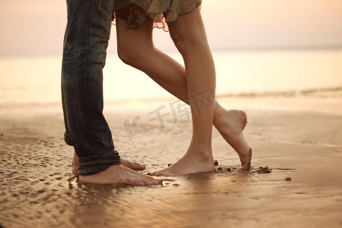 拥抱和亲吻在沙滩上恩爱的小夫妻。恋人 m图片
