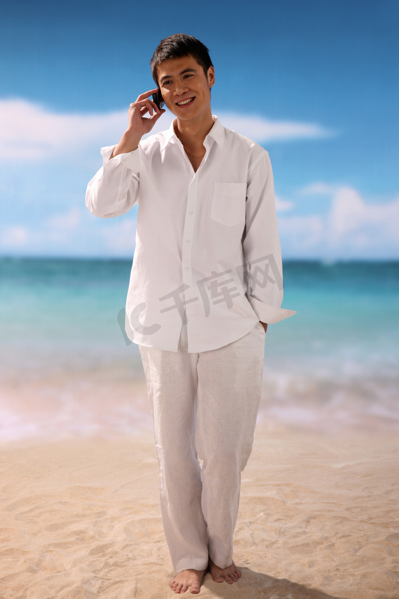东方男人在海滩打电话图片