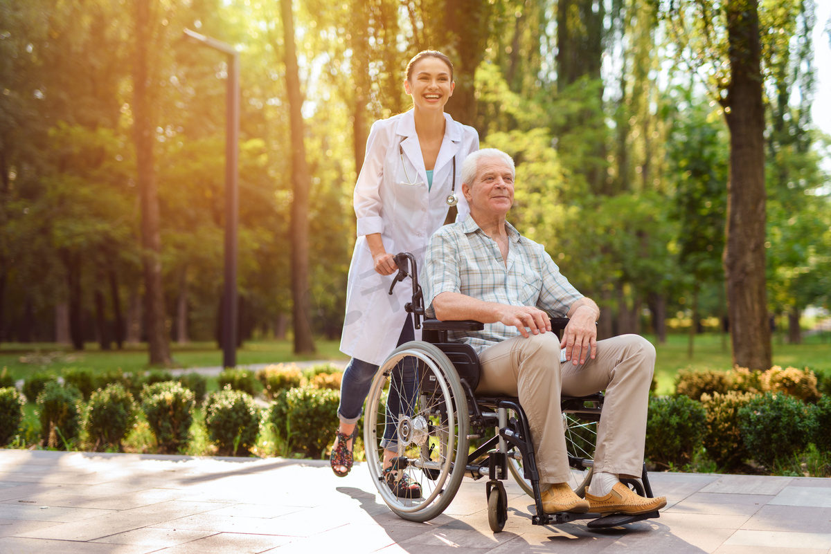 医生与老人坐轮椅在阳光公园散步图片