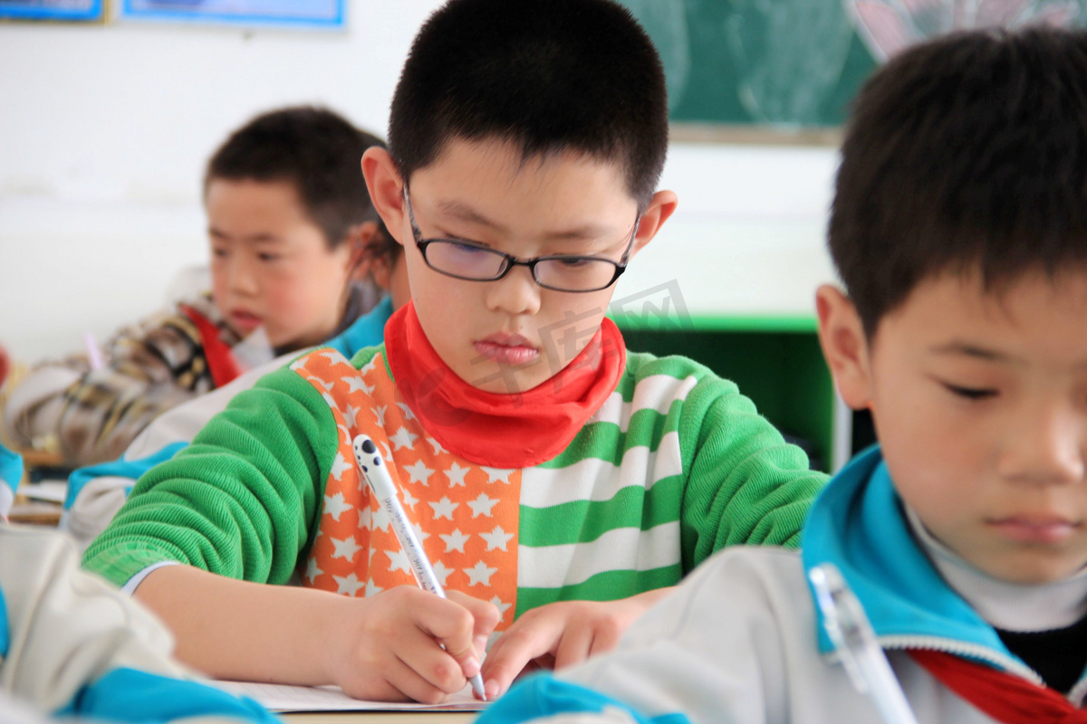 2013年4月25日，在中国东部山东省文登市一所小学上课时，一名戴眼镜的中国学生正在写字。图片