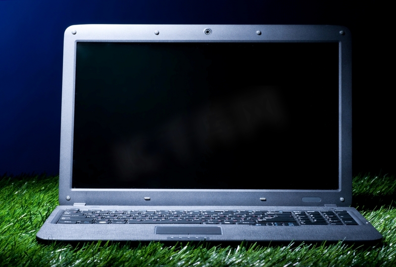 草地上的现代笔记本电脑在黑暗中照亮图片