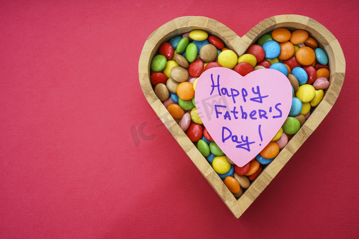 木心形状与许多糖果快乐情人节在红纸背景图片