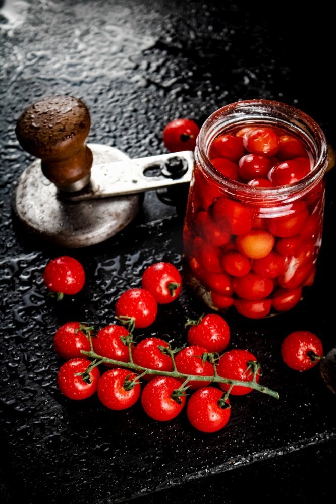 把腌制的西红柿放在石板上的罐子里。在黑色背景上。高质量的照片。把腌制的西红柿放在石板上的罐子里。图片