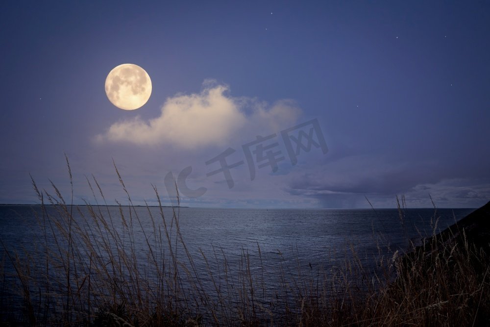 满月在海上与闪烁的星星在紫色的夜空图片