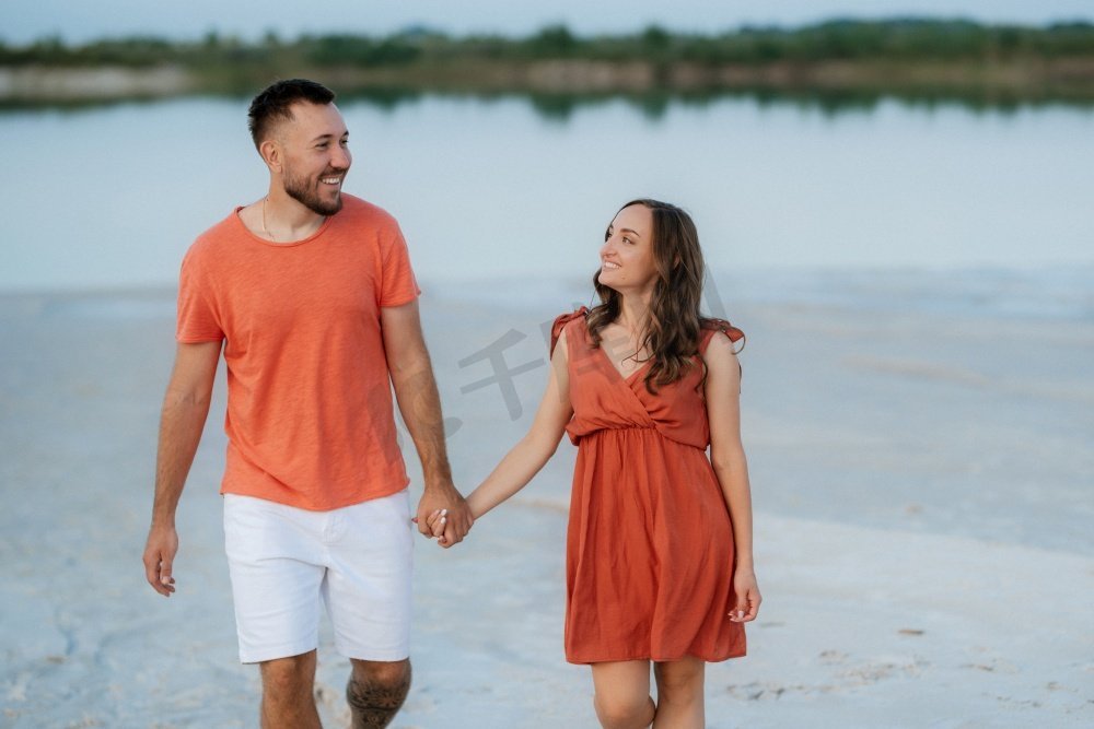 年轻夫妇橙色衣服与狗在空沙滩图片