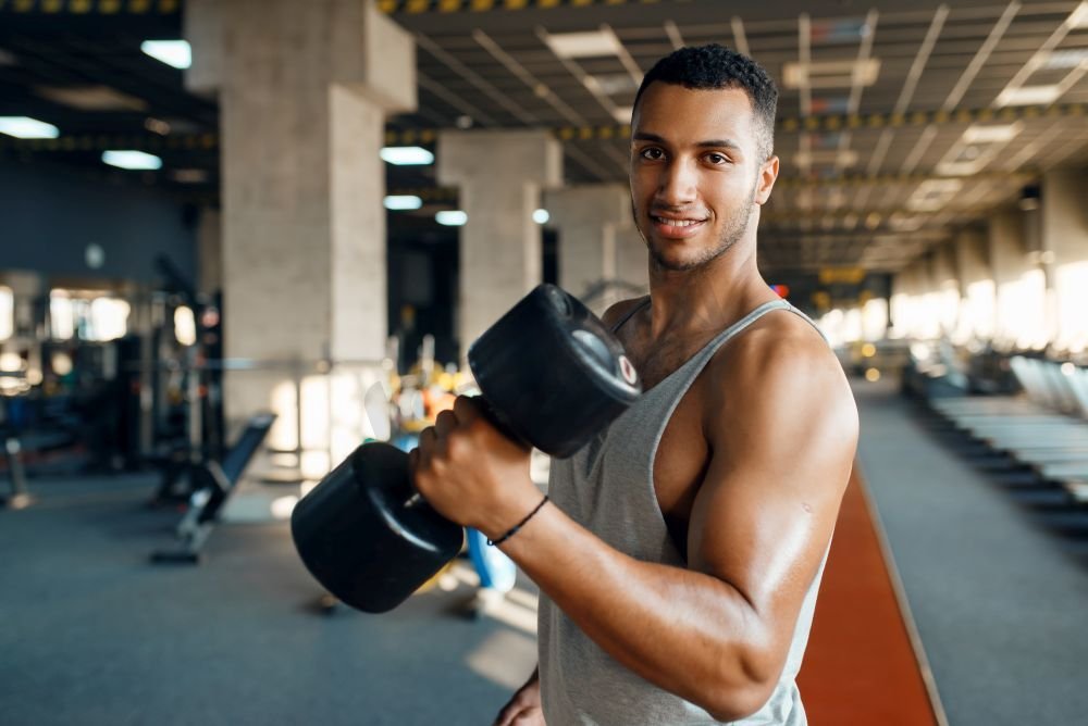 肌肉男摆出沉重的哑铃在健身房训练。体育俱乐部健身锻炼，健康的生活方式，健身运动图片