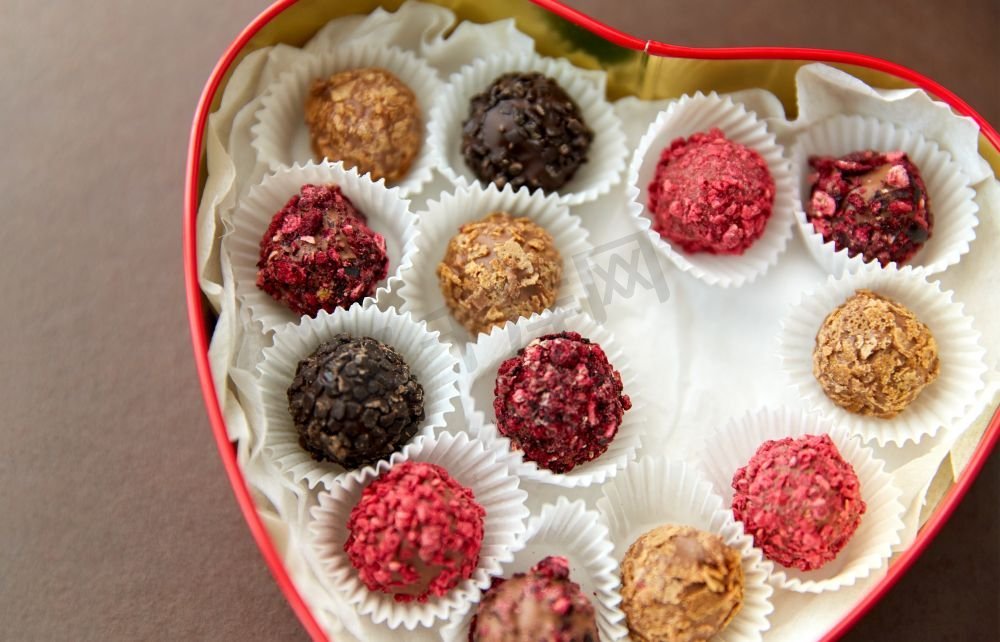 糖果，糖果和食物概念—糖果在红色心脏形状的巧克力盒在棕色背景糖果在红心形状巧克力盒图片