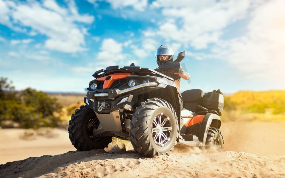 在亚视的沙场进行夏季越野探险。戴着头盔的男性车手在沙坑里骑着四轮摩托车图片