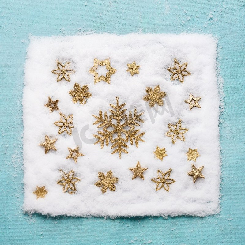 圣诞节金色雪花样式在淡蓝色背景，顶视图的雪。平躺。冬季作文和假期概念图片