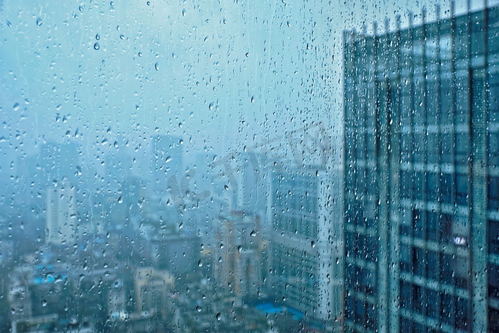 雨水滴在窗口玻璃纹理与摩天大楼在背景。雨点落在窗户上图片