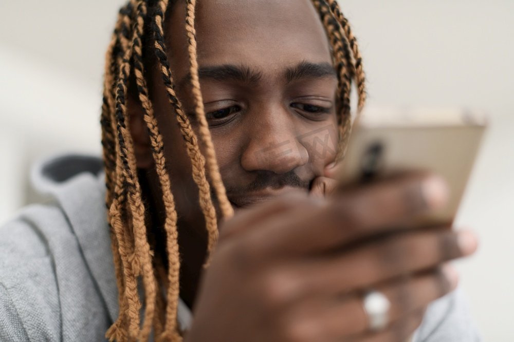 一名黑人男子在疫情期间躺在家里使用手机浏览社交媒体图片