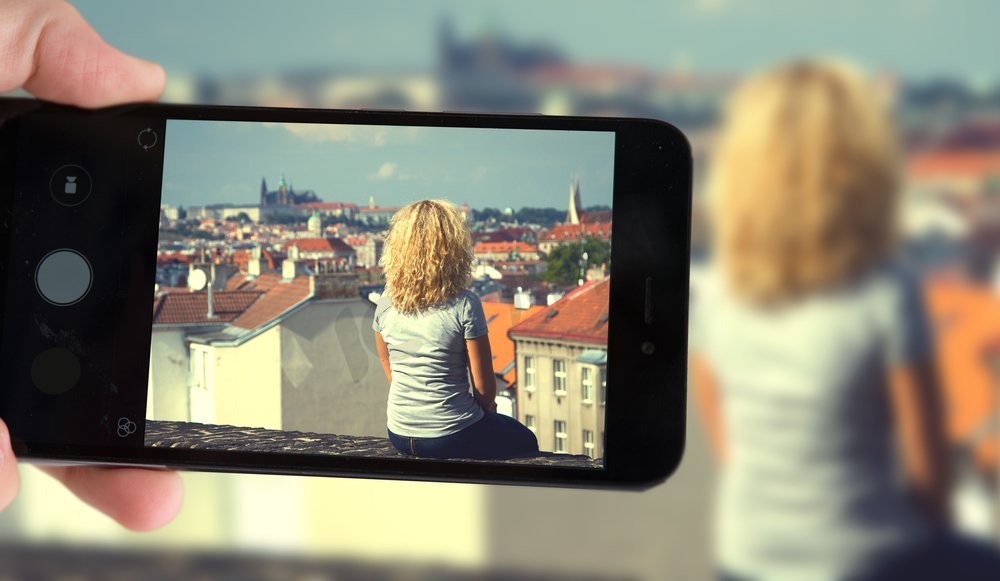 在布拉格，一名博主拍摄了一名坐在屋顶上的智能手机。坐在房顶上的女孩图片