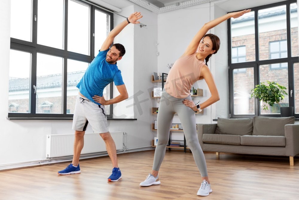 运动，健身，生活方式和人们的概念—微笑的男人和女人在家里锻炼。快乐的夫妇在家里锻炼图片