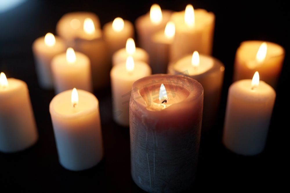 哀悼和纪念的概念-蜡烛在黑暗中燃烧在黑色的背景上。黑暗中燃烧的蜡烛覆盖着黑色的背景图片