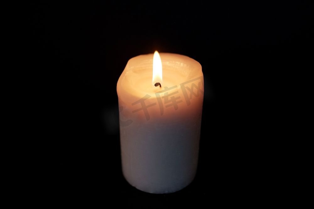 哀悼和纪念的概念-在黑暗中燃烧的蜡烛在黑色的背景上。黑暗中燃烧的蜡烛覆盖着黑色的背景图片