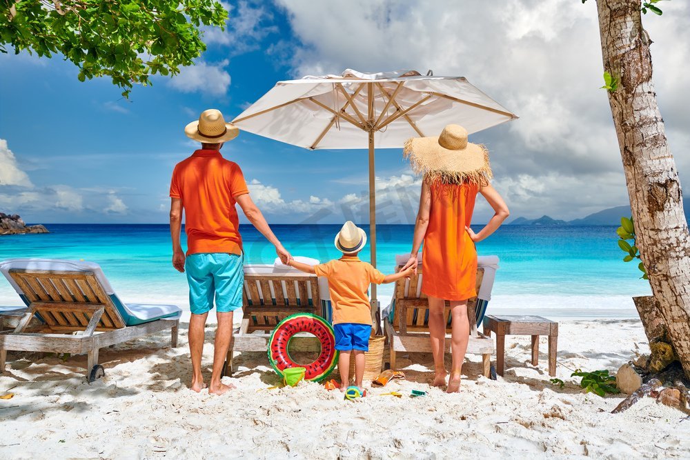 一家人在美丽的Petite Anse海滩，年轻夫妇和三岁蹒跚学步的男孩。暑假在塞舌尔，马埃岛。图片