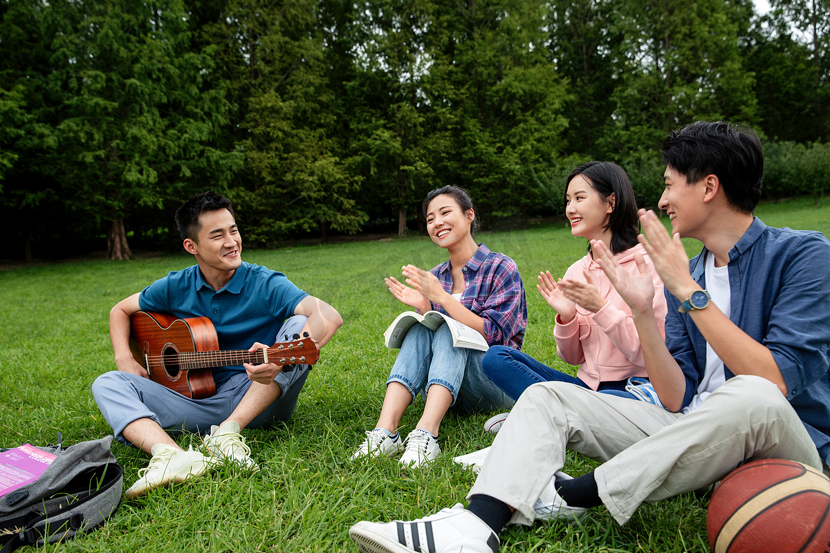快乐的大学生在草地上弹吉他唱歌图片