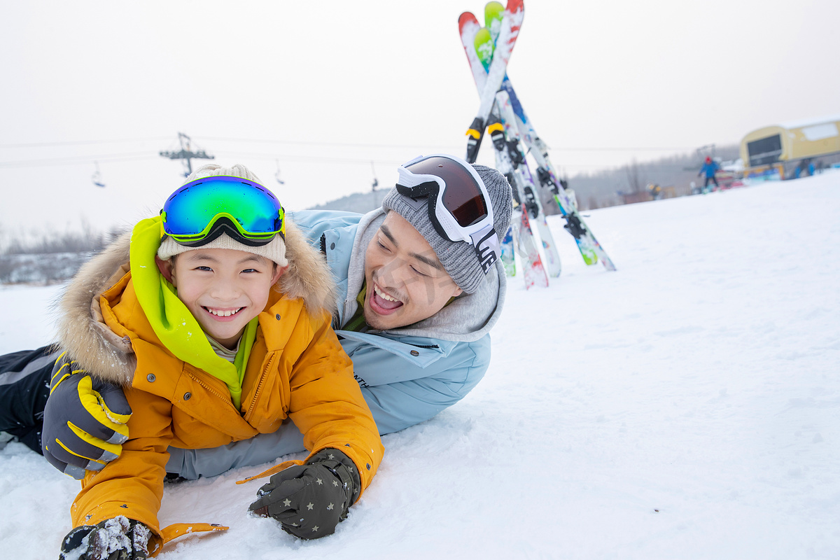 滑雪场内抱在一起打滚的快乐父子图片