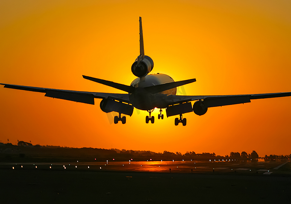 一架客机在夕阳的背景下起飞。图片
