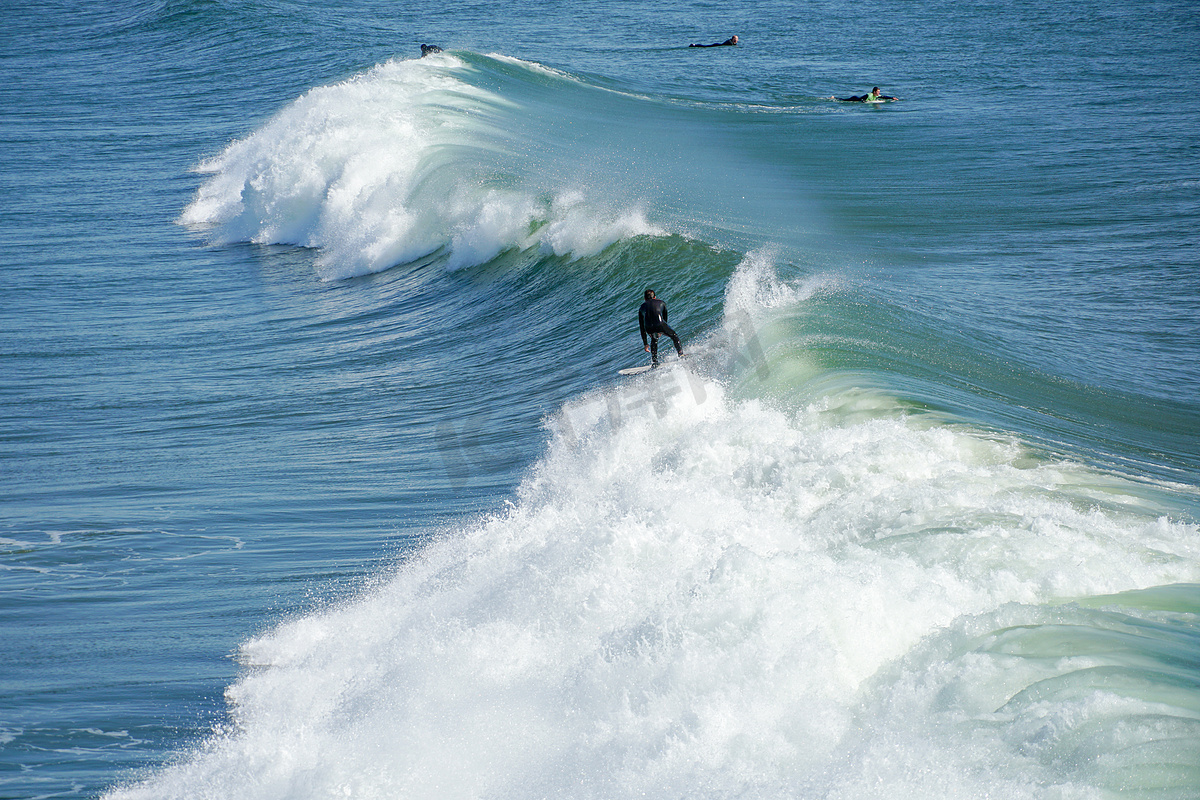 在美国加利福尼亚州圣地亚哥北部的欧申赛德享受巨浪的男性冲浪者。图片